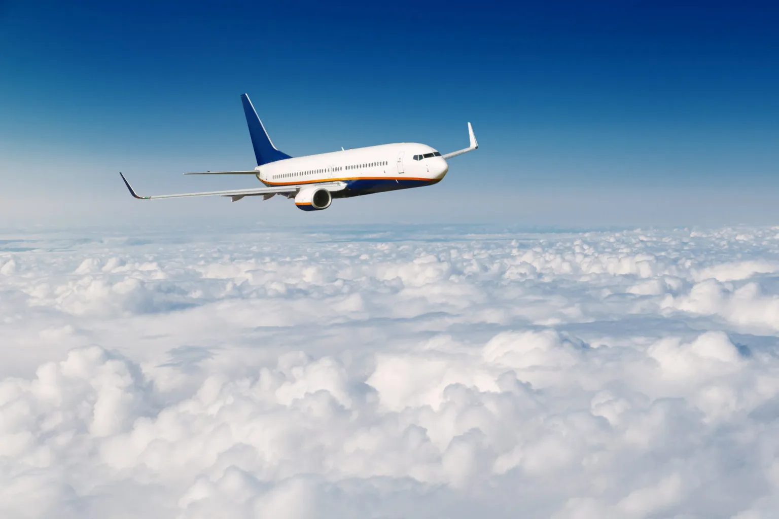 commercial-airplane-flying-above-clouds-on-blue-sk-2021-08-26-17-11-01-utc-scaled